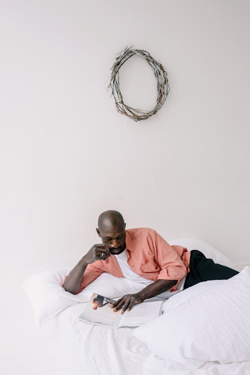 Free Photo of a Man Reading a Magazine on a Bed Stock Photo
