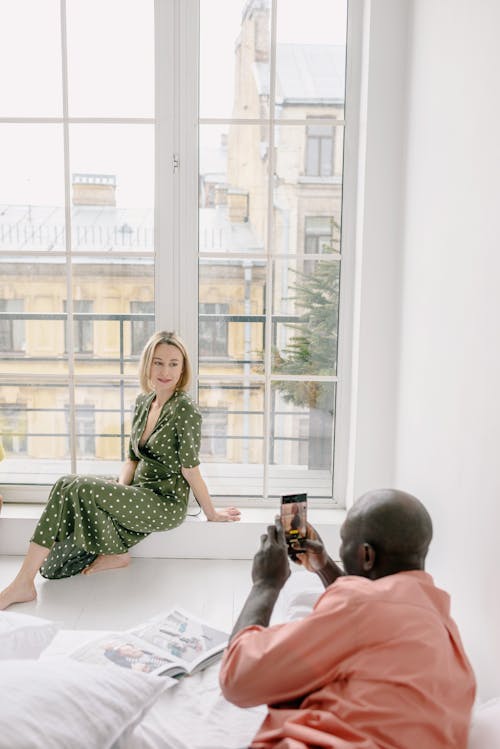 Free A Man Taking Picture of His Wife while Sitting Near the Glass Window Stock Photo