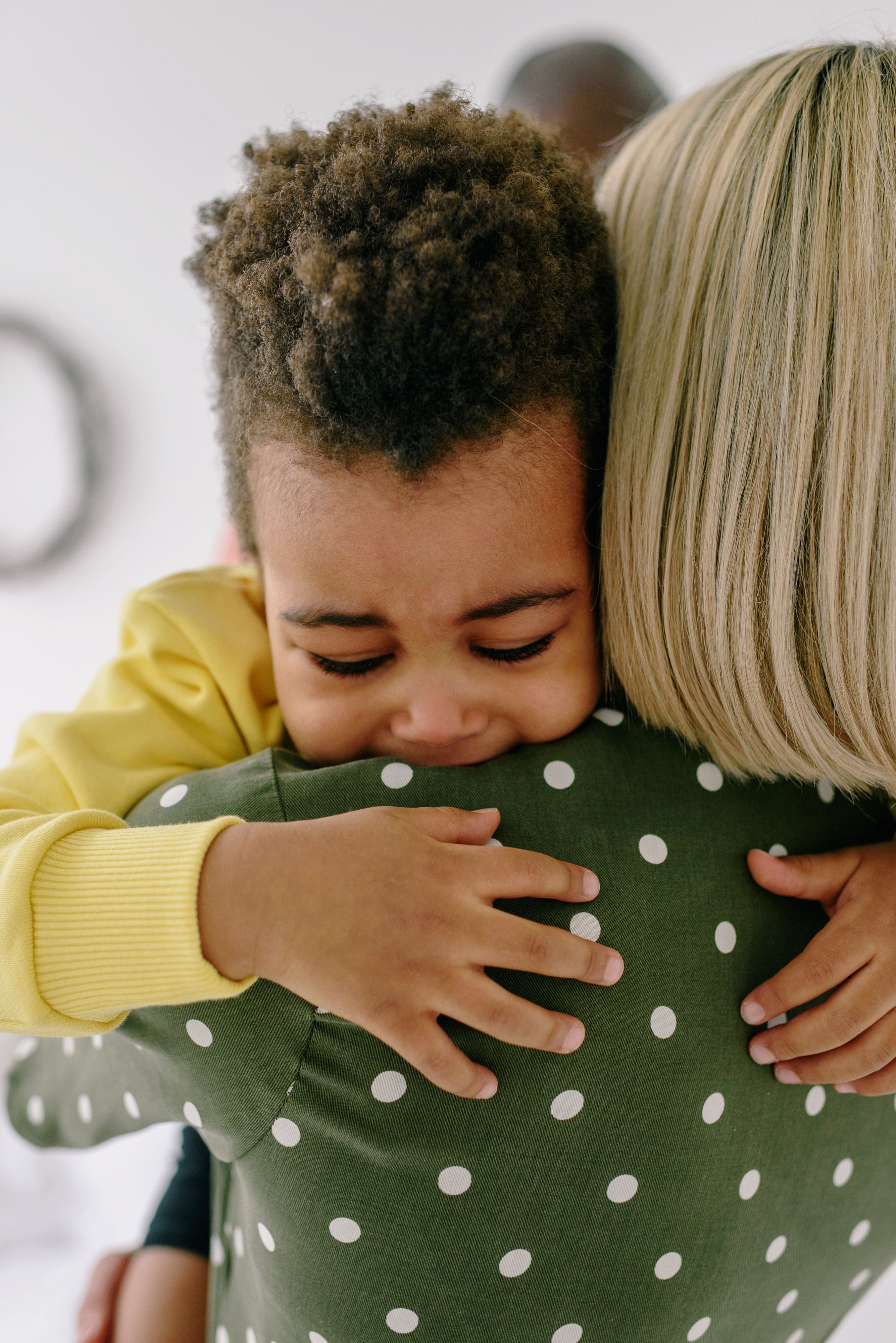 A caring mother comforts her crying child in a close embrace, showcasing love and support.