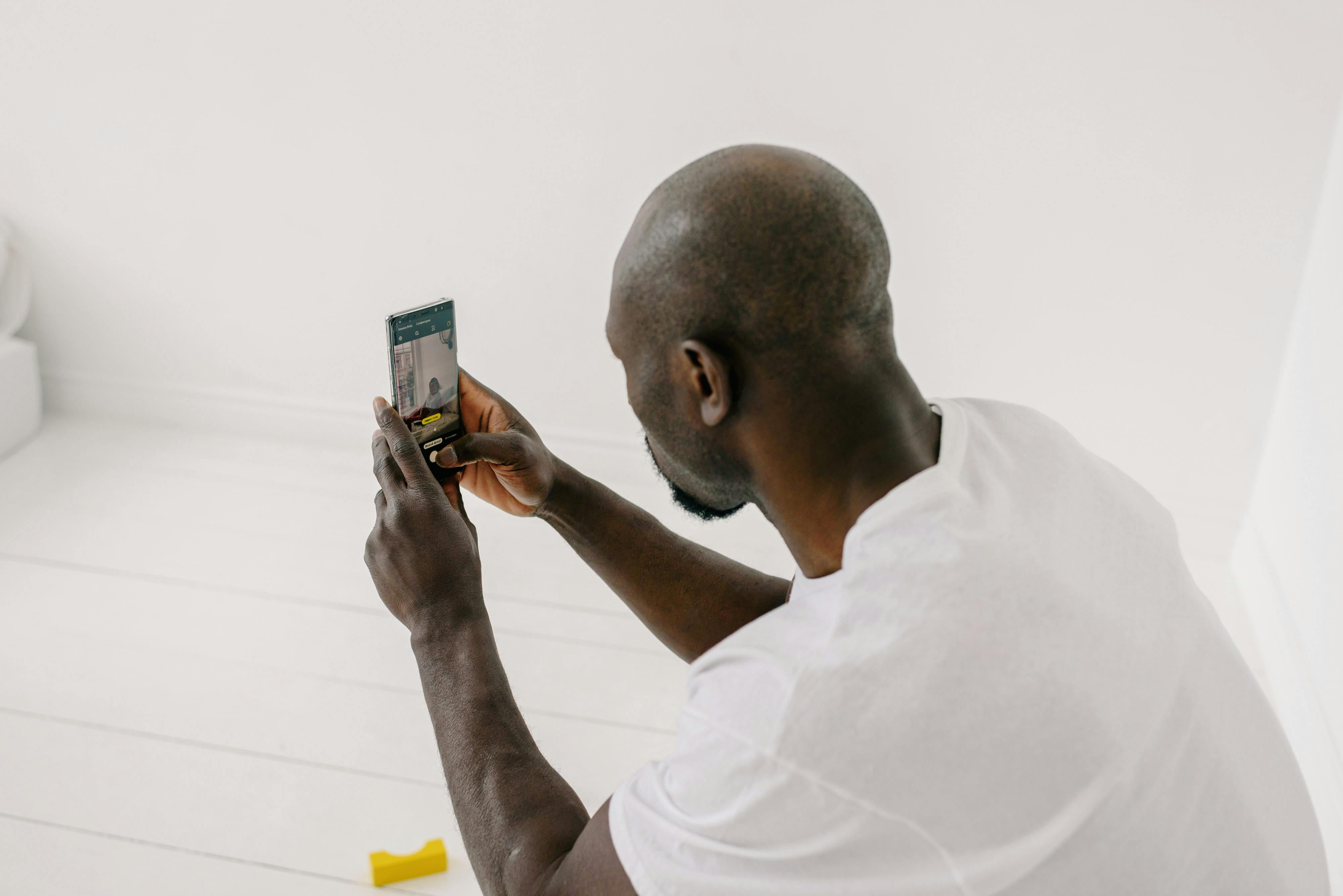 bald african american man taking photo with mobile phone