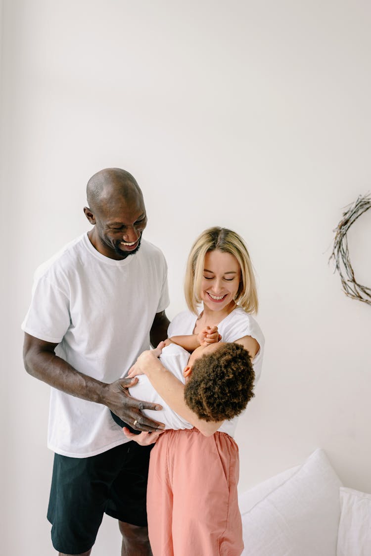 Woman Holding A Child And A Father Standing And Smiling