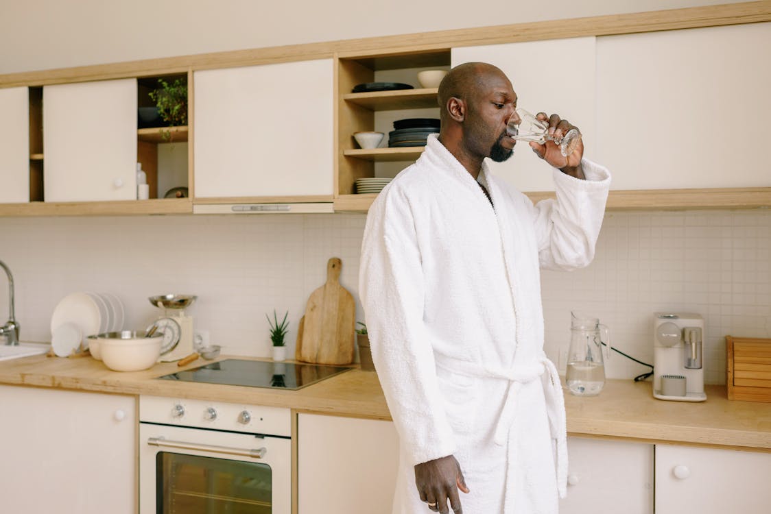 A person wearing a bathrobe and drinking water