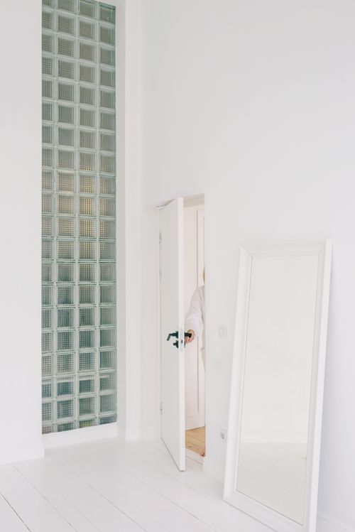 Free A stylish, minimalist room interior with a partially opened door and a standing mirror. Stock Photo