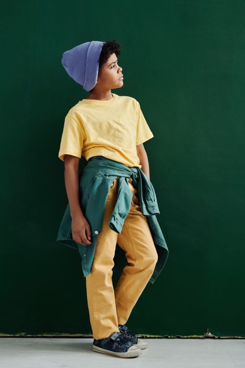 Free Fashionable boy posing in vibrant clothing with a green background, showcasing modern style. Stock Photo