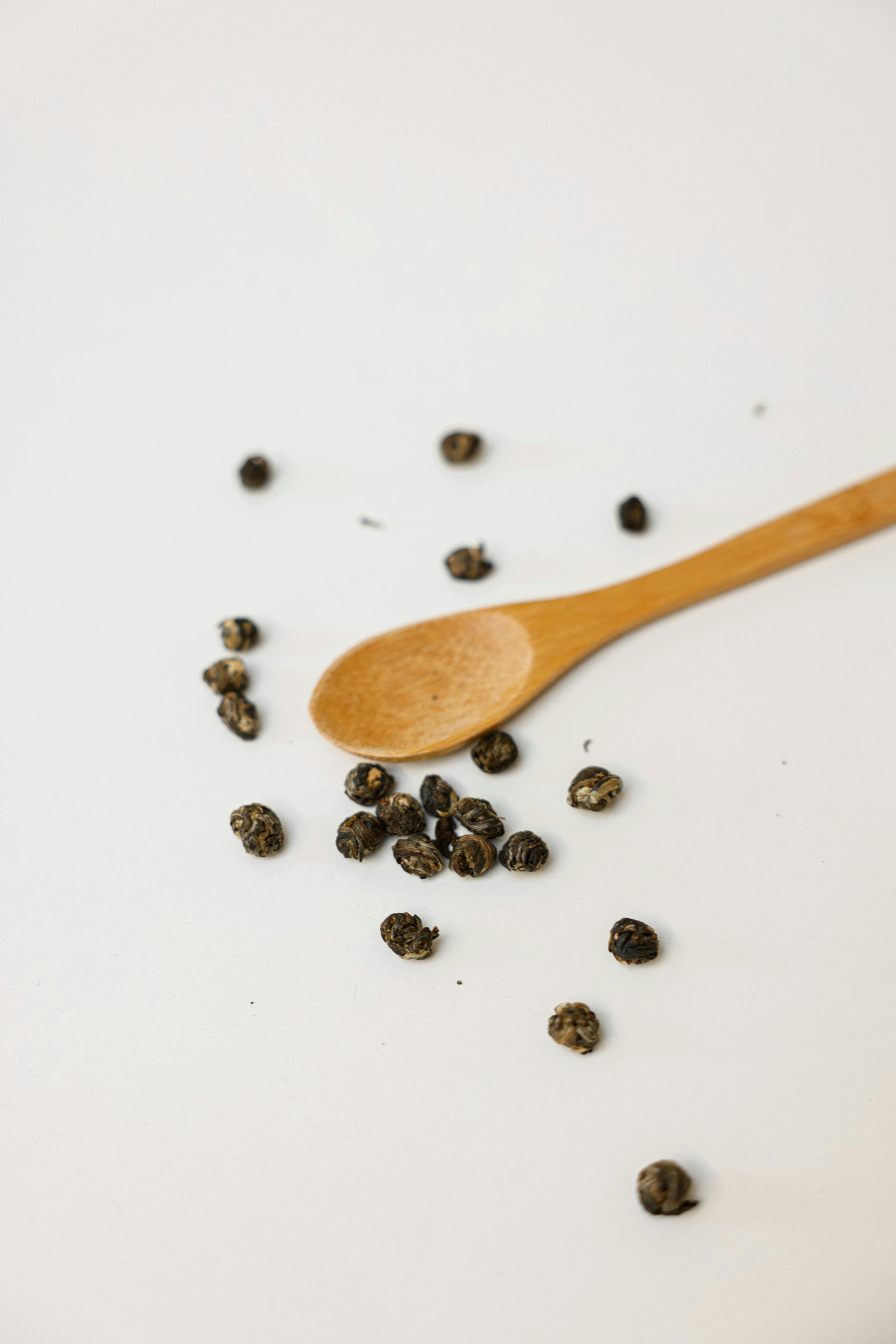 Hand seasoning with a black pepper shaker a fresh salad bowl mixed green  leaves, eggs, black olives and tomato on a wooden table with cutlery.  Nature blurred background. Vertical photography Stock Photo