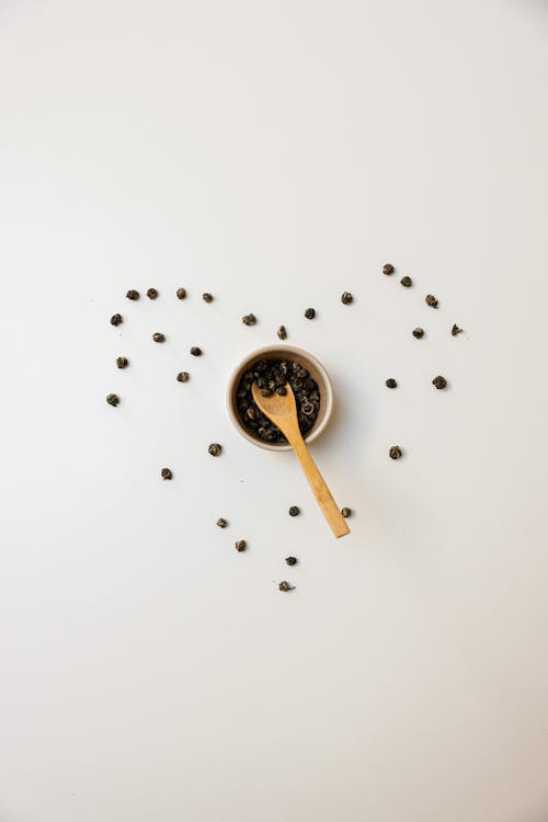 Brown Wooden Spoon on a Ramekin with Peppercorns 
