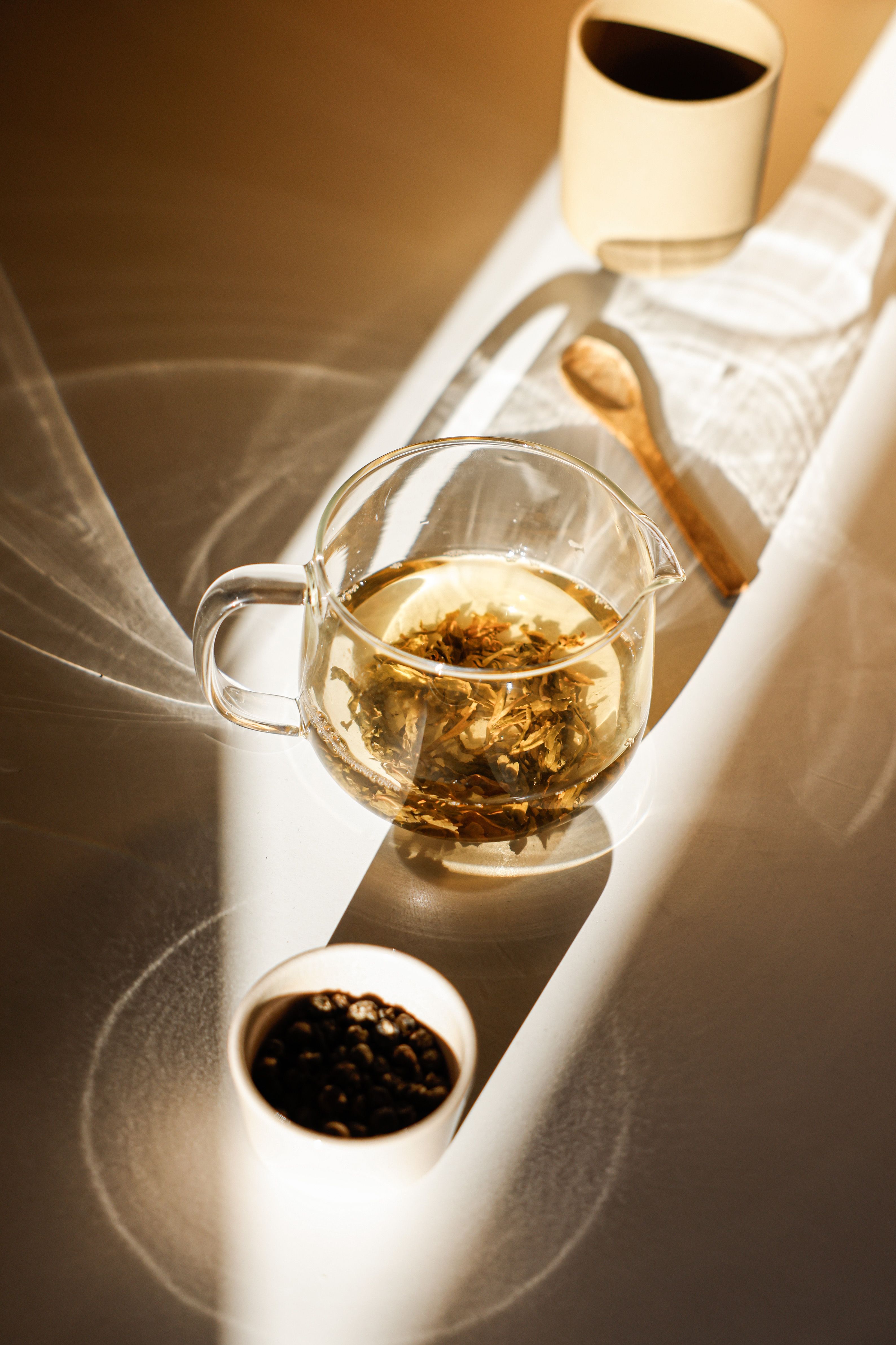 Loose-leaf tea brewing in a glass teapot beside ceramic cups