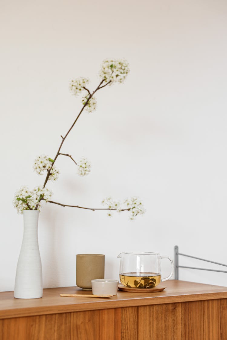 Still Life With A Fruit Tree Branch With White Flowers And Tea On Cupboard