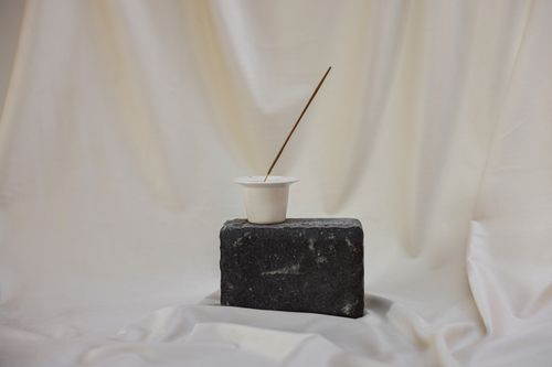 Free Simple arrangement of a cup and stick on a stone against a white curtain backdrop. Stock Photo