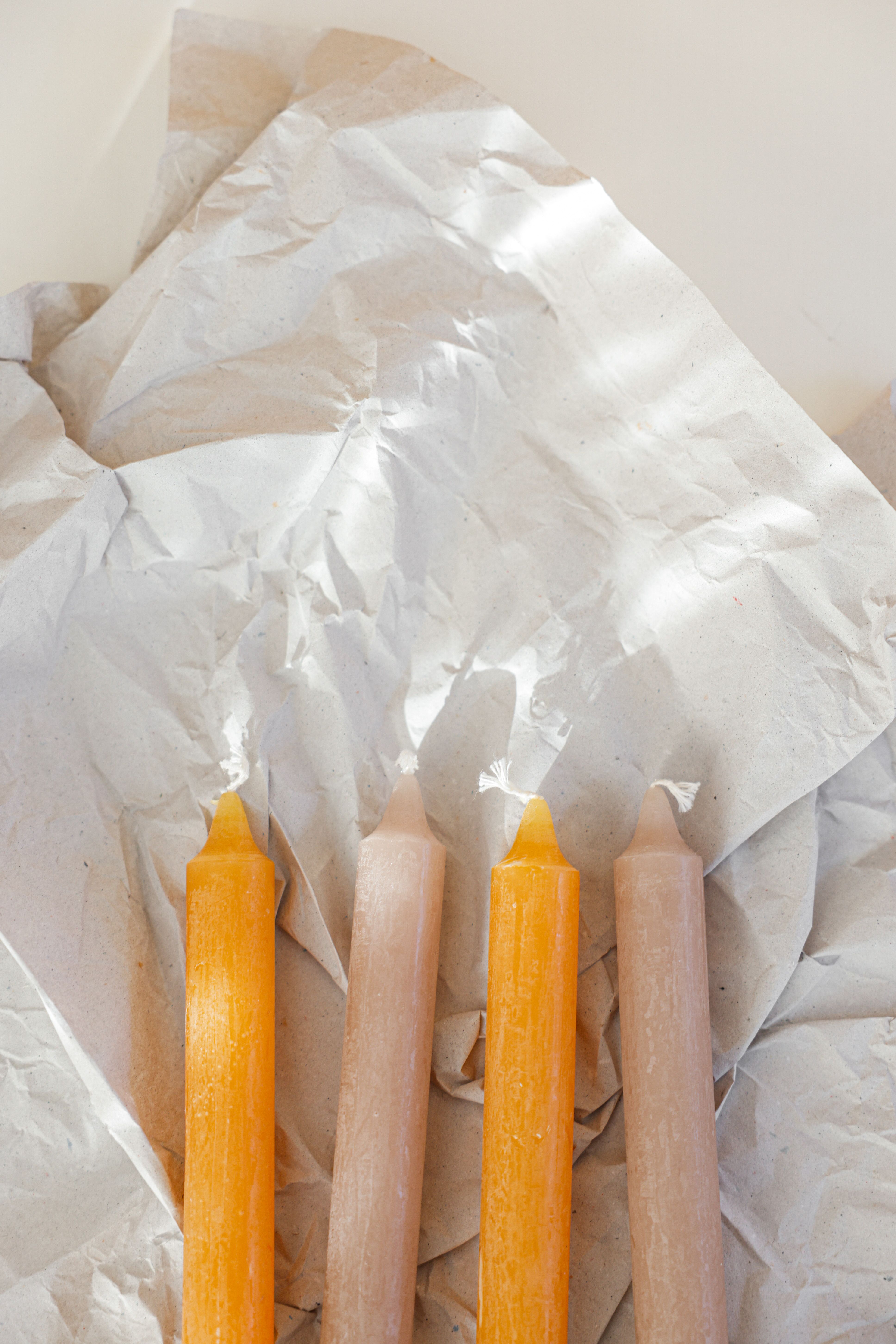 Four candles on crumpled paper create a minimalist and warm atmosphere.
