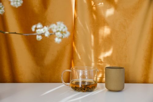Free Elegant composition of tea in a glass cup and blooming branch against a warm background. Stock Photo