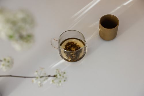 Free Glass cup of herbal tea and flowers in a serene minimalist setting. Stock Photo