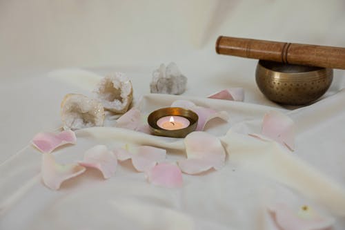 Lighted Candle Beside a Tibetan Singing Bowl on White Linen