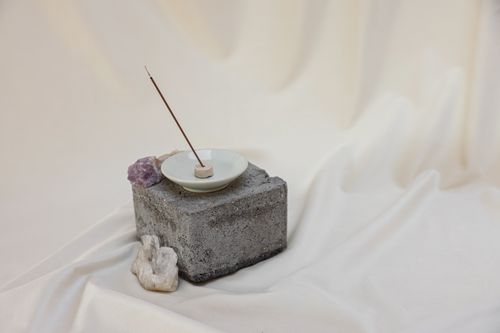 Free A minimalist zen setup featuring a burning incense stick, amethyst, and stones for meditation. Stock Photo