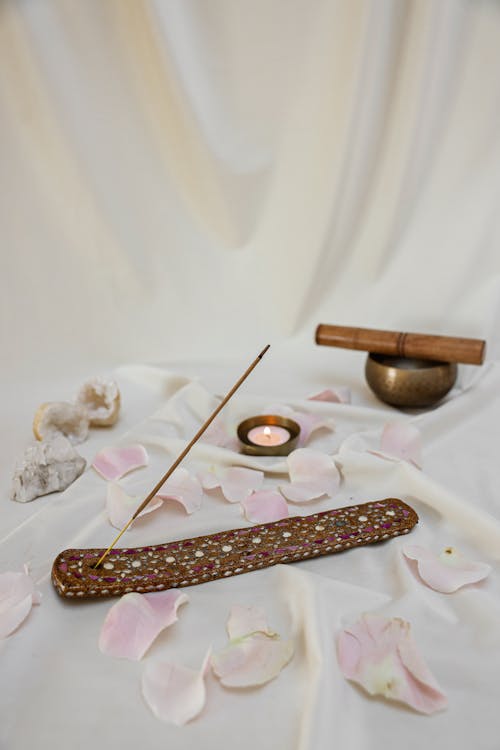 Free Lighted Candle Beside a Tibetan Singing Bowl and Incense Stick on White Linen Stock Photo