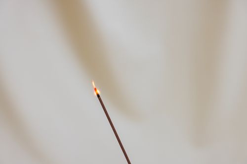 Free Close-up of a burning incense stick against a neutral background, embodying simplicity and calm. Stock Photo