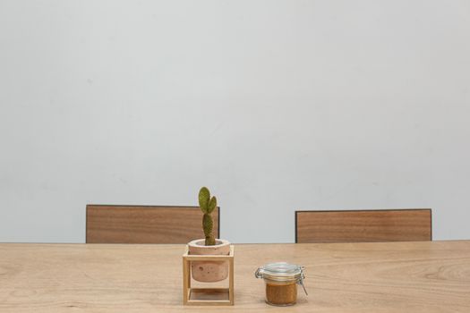 Simple minimalist dining setting featuring cactus and jar on wooden table.