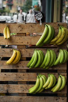 A Green and Yellow Banana Fruits Hanging on a Wooden Crate