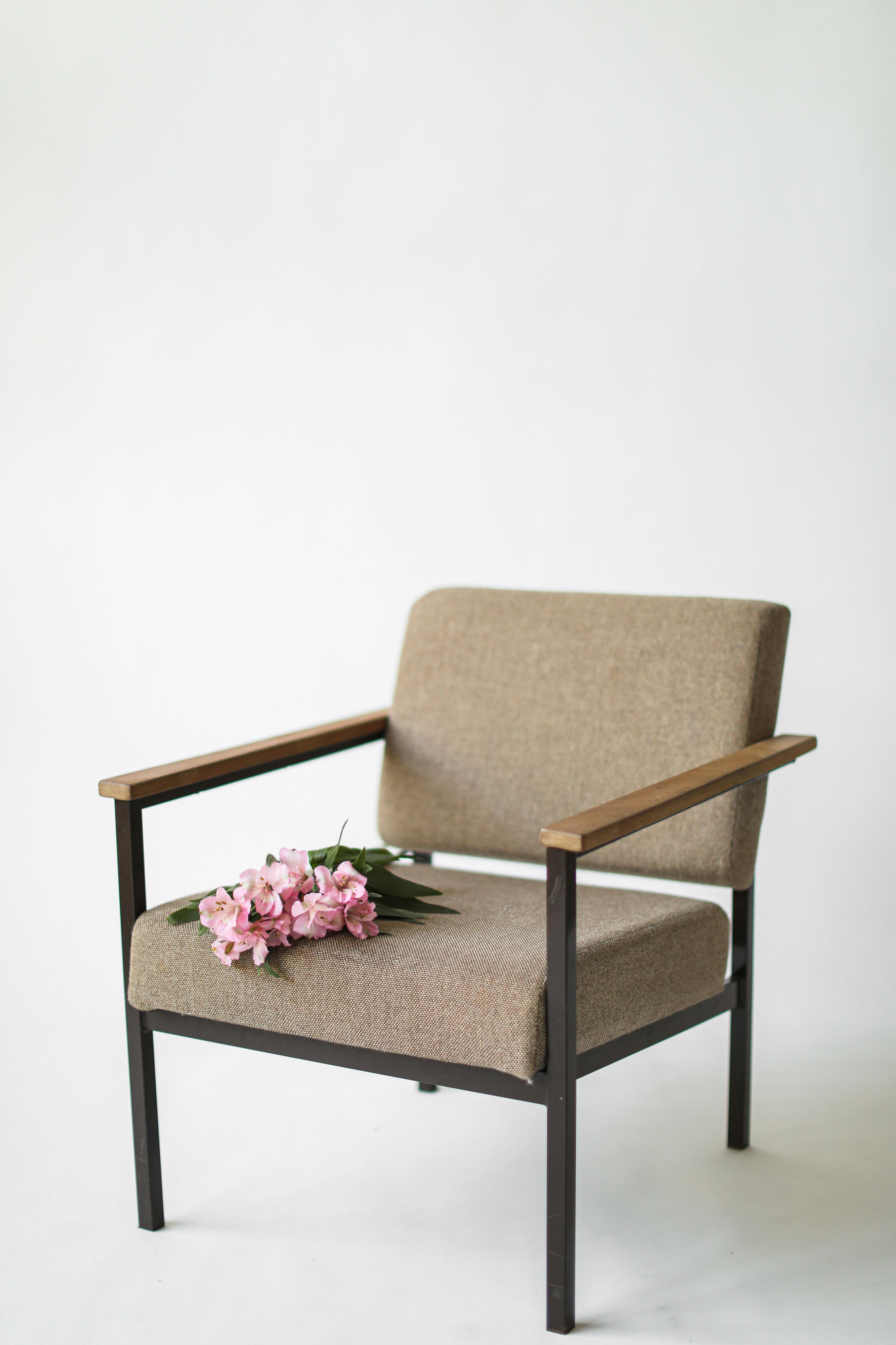 Stylish armchair with a pink flower bouquet on a clean white background.