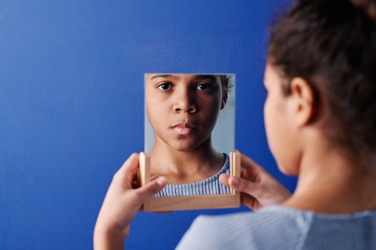 A Young Girl Holding A Mirror