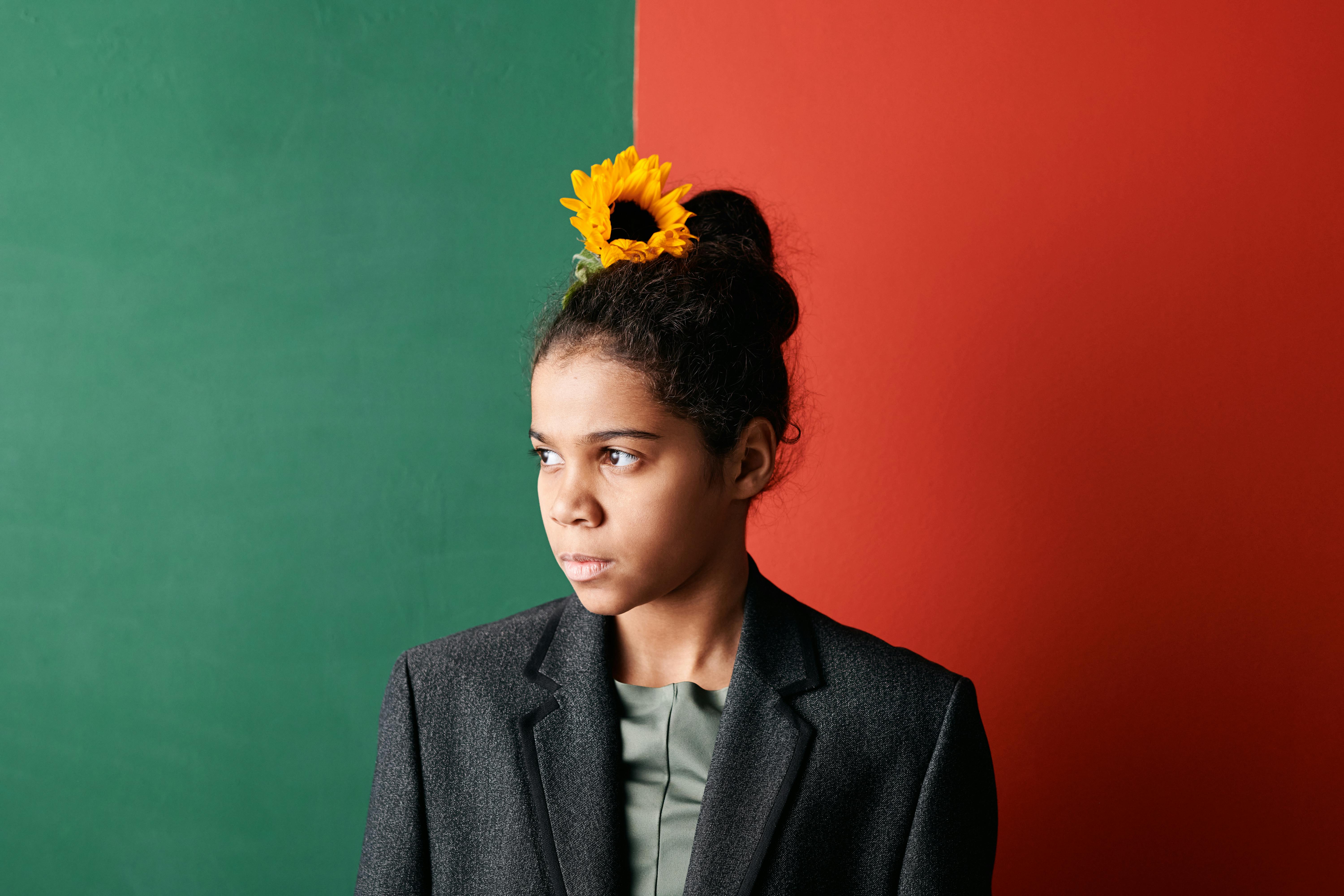 a young girl wearing a blazer with sunflower on her hair