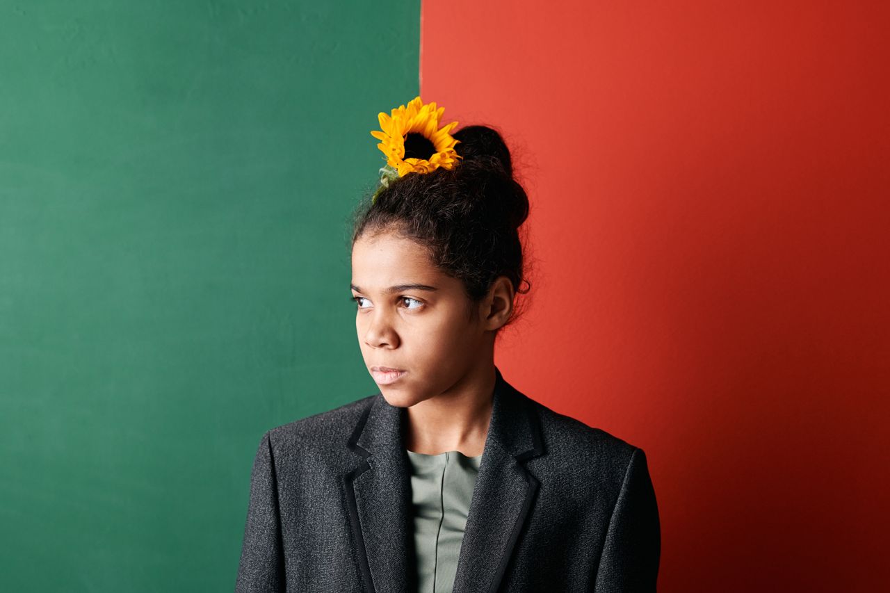 portrait of a young black woman in a blazer with a sunflower in her bu