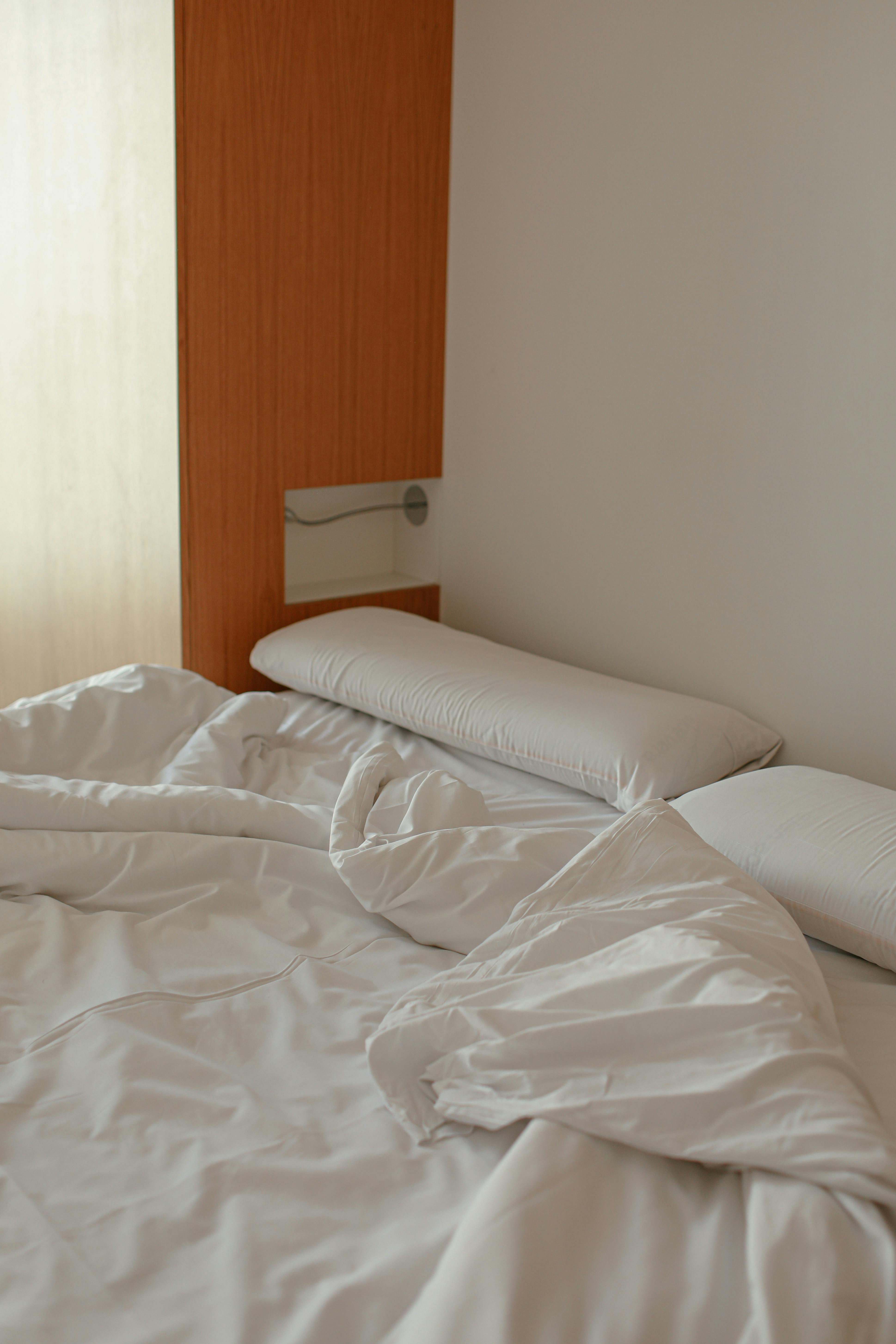 Cozy and minimalist bedroom with white linens and pillows, perfect for relaxation.