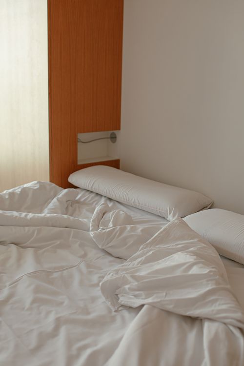 Free Cozy and minimalist bedroom with white linens and pillows, perfect for relaxation. Stock Photo