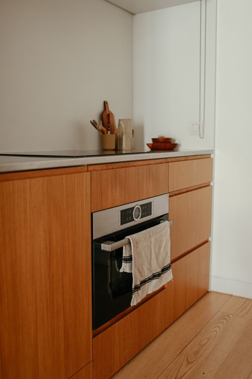 Free Modern minimalist kitchen featuring wooden cabinets and built-in oven. Stock Photo