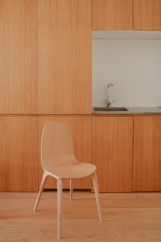 A modern minimalist kitchen interior featuring wooden cabinets and sleek design.