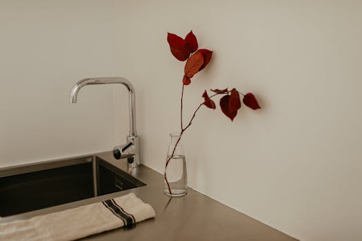 Simple and elegant kitchen design featuring a minimalist setup and red leaves in a vase.
