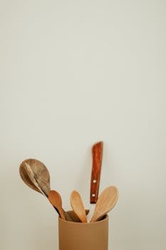 A collection of wooden kitchen utensils in a neutral-toned holder for a minimalist look.