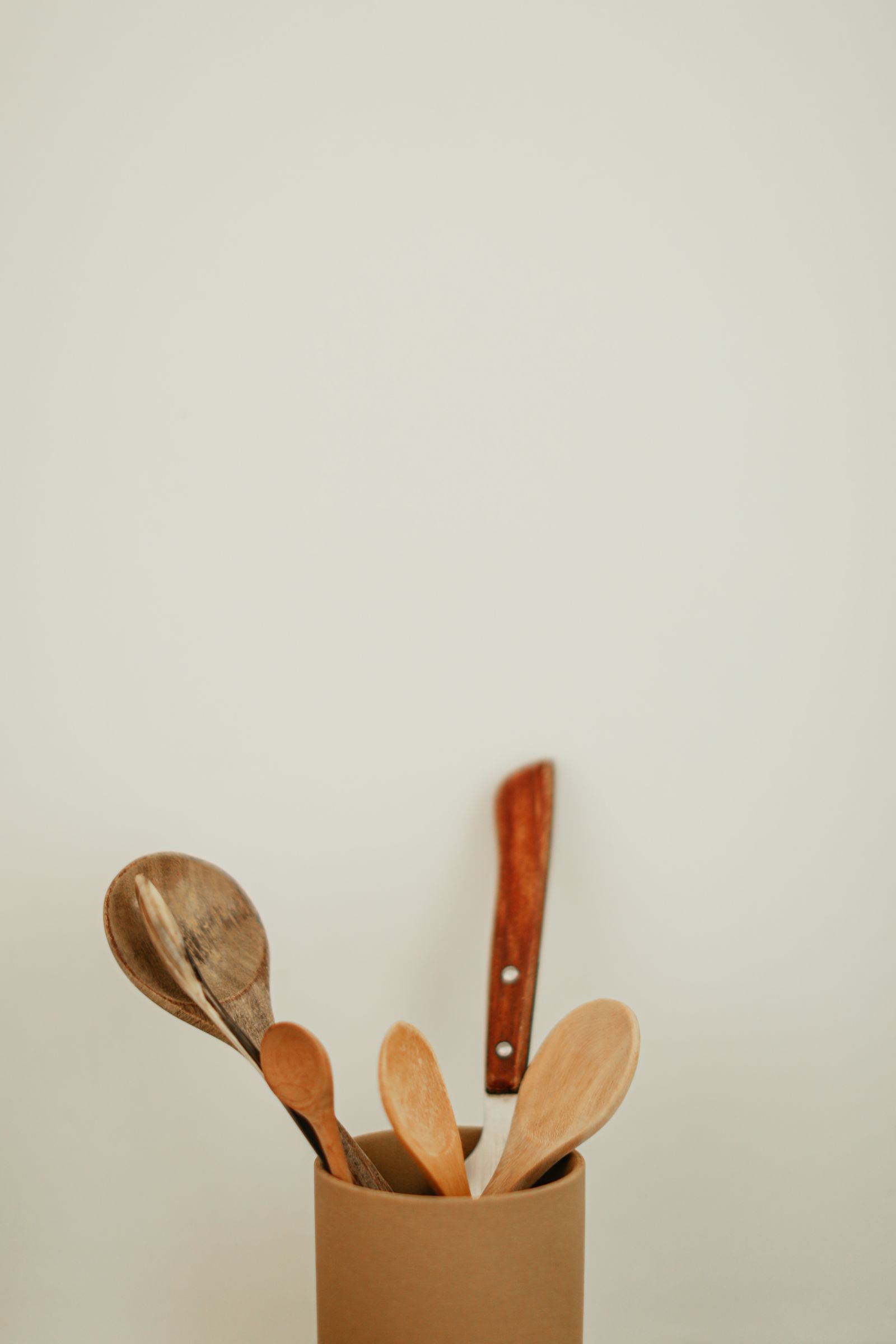 Wooden spoons and a knife on a pale surface