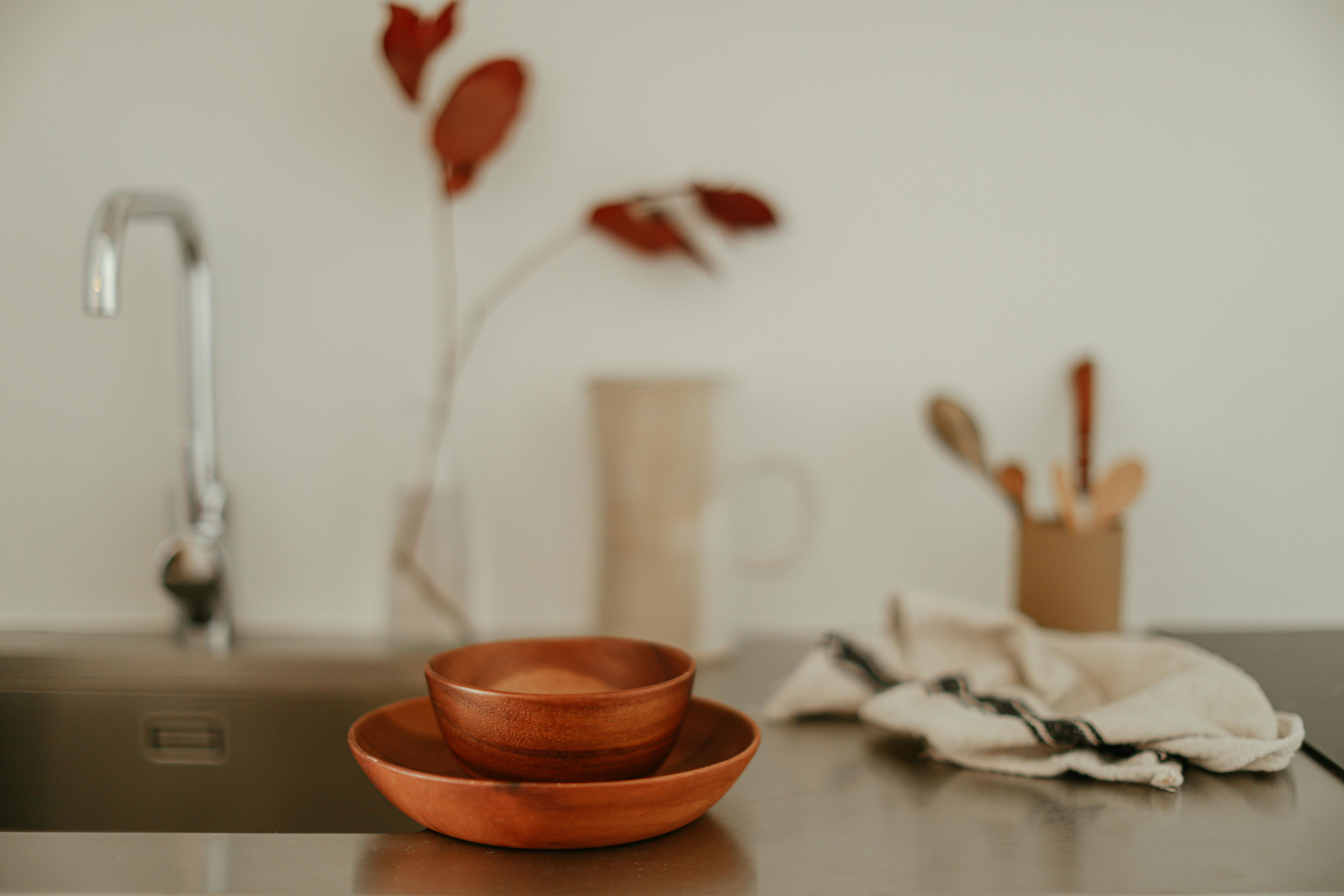 A serene, minimalist kitchen setup featuring wooden bowls and a stainless steel faucet.