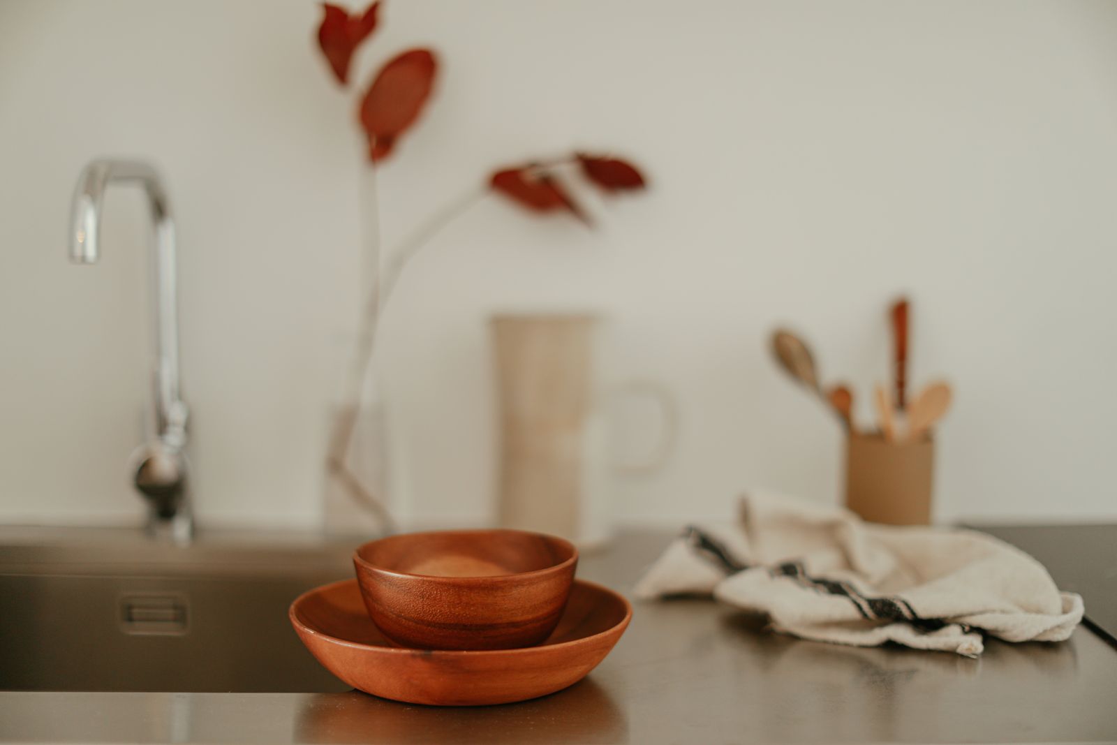 Wooden bowl beside a folded linen towel on a quiet kitchen countertop
