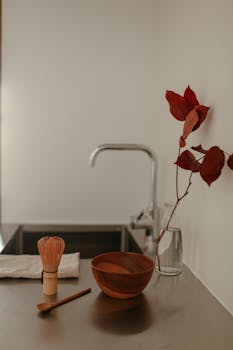 A serene and minimalist kitchen featuring a wooden bowl, bamboo whisk, and simple decoration.