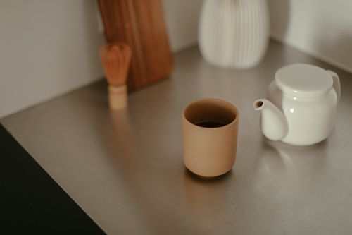 Free Minimalist kitchen scene featuring a teapot and a ceramic cup on a counter. Stock Photo