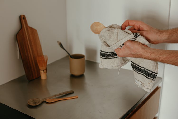 Person Wiping A Wooden Spoon