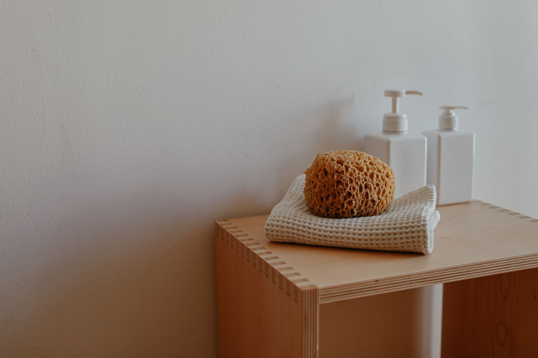 Bathroom shelf with folded cloth, sponge and a small group of pump bottles