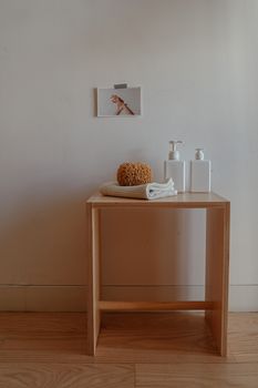 Wooden table with toiletries, sponge, and a photo against a soft white wall.