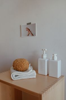 Minimalist bathroom decor featuring soap dispensers, sponge, and towel on a wooden shelf.
