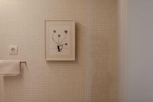 Free A modern bathroom featuring a framed plant illustration on tiled wall, perfect for interior inspiration. Stock Photo