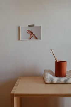 A minimalist bathroom scene with a wooden toothbrush on a wooden table.