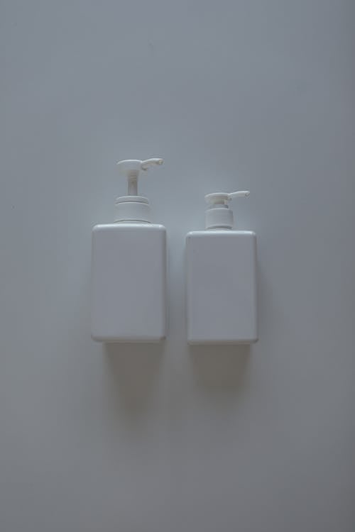 A Pair of White Pump Bottles on White Surface