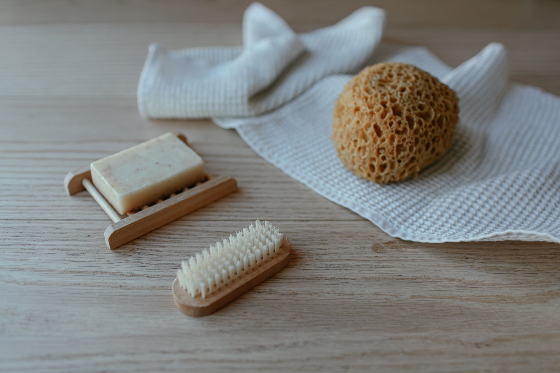 Minimalist flat lay of soap, brush, and sponge on towels, perfect for a serene bath scene.