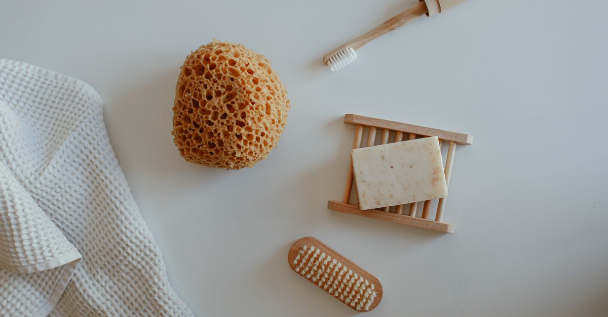 Top view of minimalist bathroom essentials including soap, sponge, and tools on a white background.