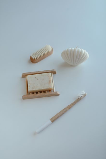 Bath bar, wooden dish and a shell candle on a pale surface — photo by Cup of Couple on Pexels