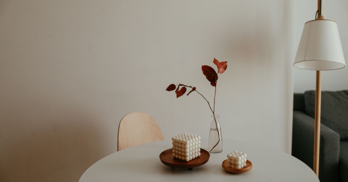 White decorative candles on wooden trays on a minimalist table with warm home styling