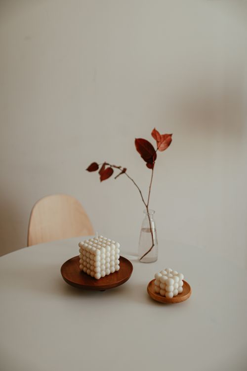 Free Elegant minimalist still life featuring bubble candles and a branch in a vase on a round table. Stock Photo