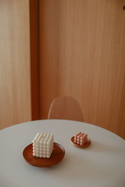 Free Stylish minimalist setup of geometric candles on a round table in a wooden interior. Stock Photo